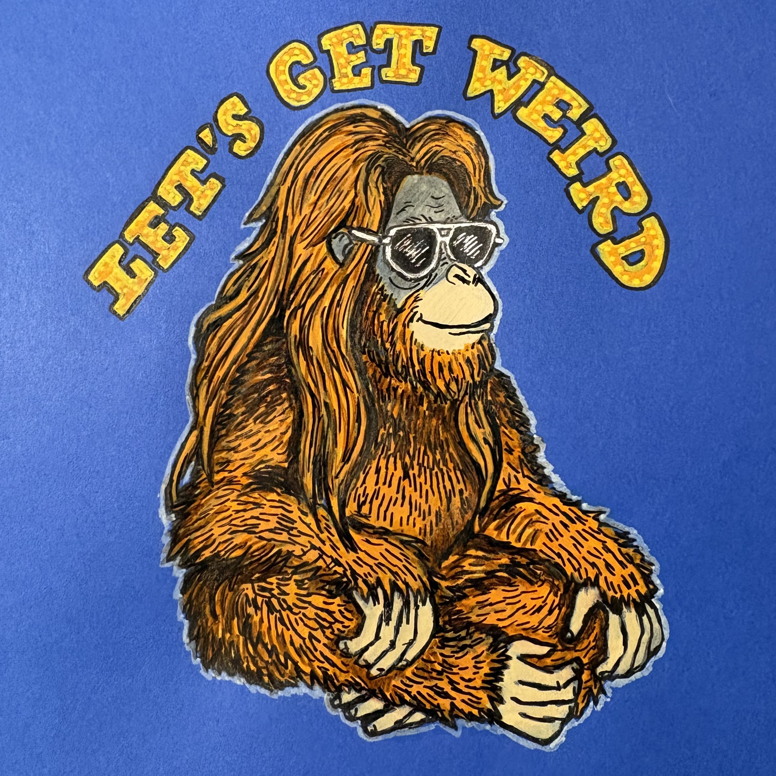 A mixed media illustration of a long haired orangutan sitting cross legged and looking serene with the words Let's Get Weird! above. The drawing is against a blue background.